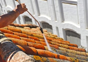 Operator Cleaning An Old Roof With High Pressure Water